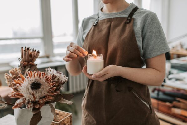 person in brown apron holding white candle